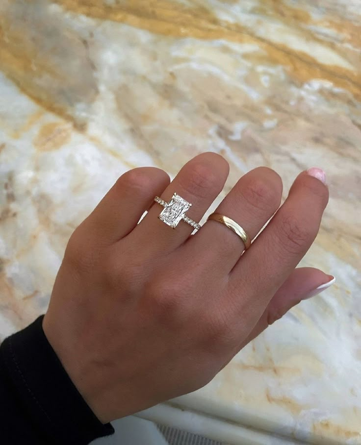 a woman's hand with two gold rings on it and one diamond ring in the middle