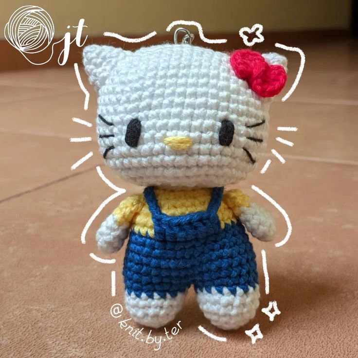 a crocheted hello kitty doll wearing overalls and a bow in her hair