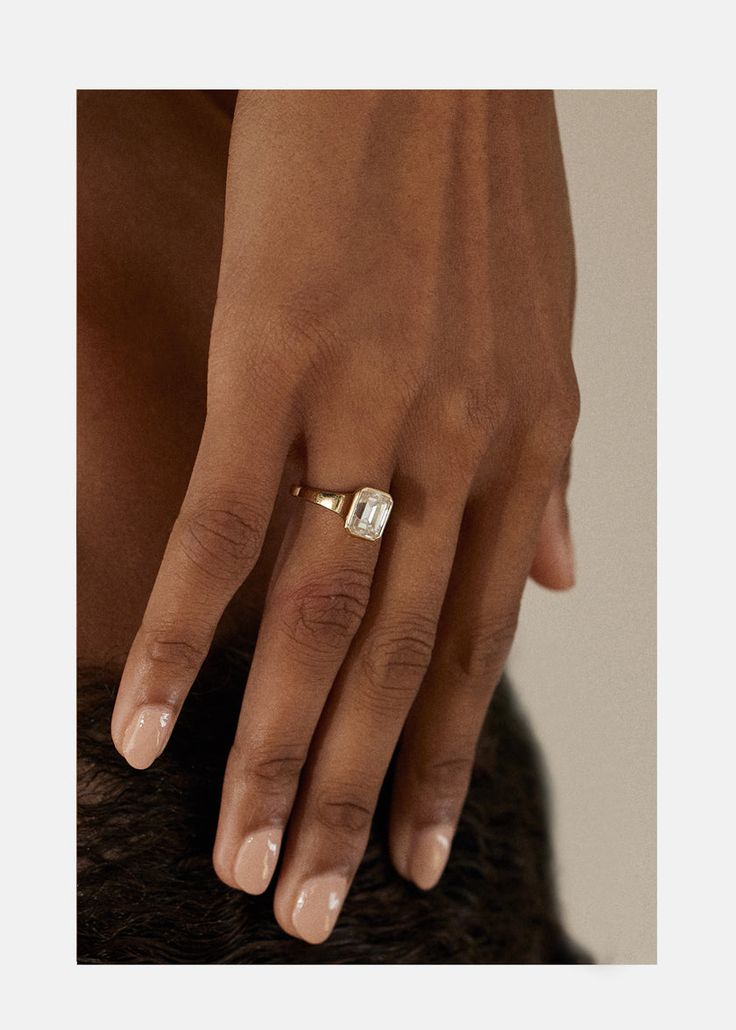 a woman's hand with a gold ring on her left side, and a diamond in the middle