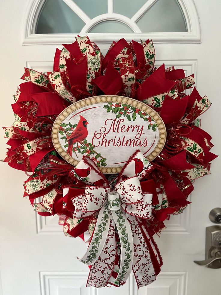 a red and white christmas wreath hanging from the front door with merry christmas written on it