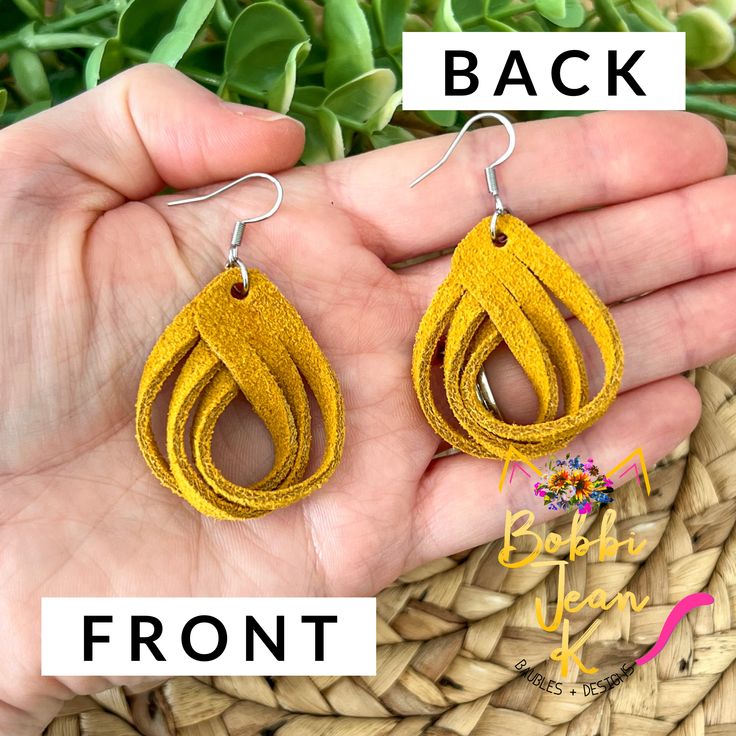 a pair of yellow leather earrings on a person's hand