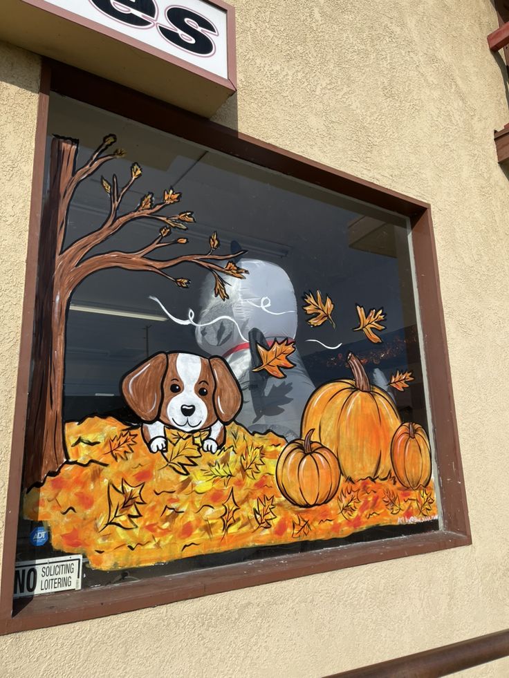 a window with a dog and pumpkins painted on the glass in front of it