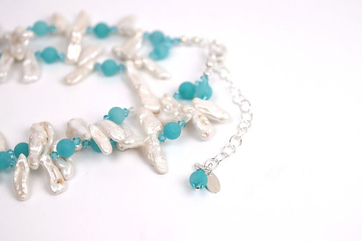 Dive into a sea of serenity with this Ocean Breeze necklace. The two strands of white Biwa pearls symbolize femininity and purity, while the matte turquoise rounds add a touch of color and vibrancy. Swarovski© crystal adds a touch of sparkle, making this necklace perfect for all occasions. The silver adjustable chain makes it easy to customize the length, so you can wear it any way you like. Soak up the sun and feel the sand between your toes while wearing this beautiful piece of jewelry. Elegant Turquoise Beaded Necklaces For Weddings, Elegant Double Strand Turquoise Beaded Necklace, Elegant Turquoise Double Strand Beaded Necklaces, Elegant Turquoise Multi-strand Jewelry, Elegant Multi-strand Turquoise Jewelry, Elegant Turquoise Necklace With Pearl Drop, Elegant Turquoise Pearl Drop Necklace, Elegant Multi-strand Turquoise Beaded Necklaces, Turquoise Pearl Necklace With Pearl Drop