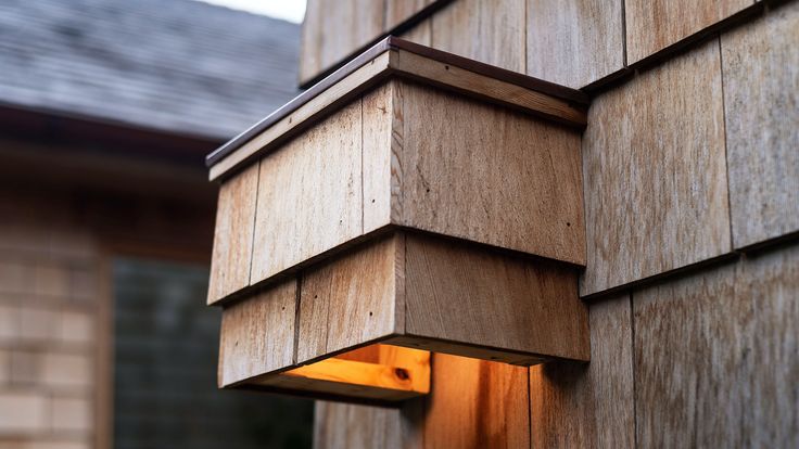 a light that is on in the side of a building next to a wall with wood panels