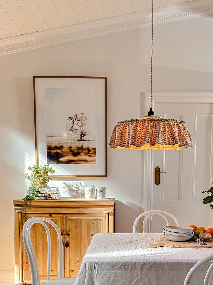 a dining room table with white chairs and a chandelier hanging from the ceiling