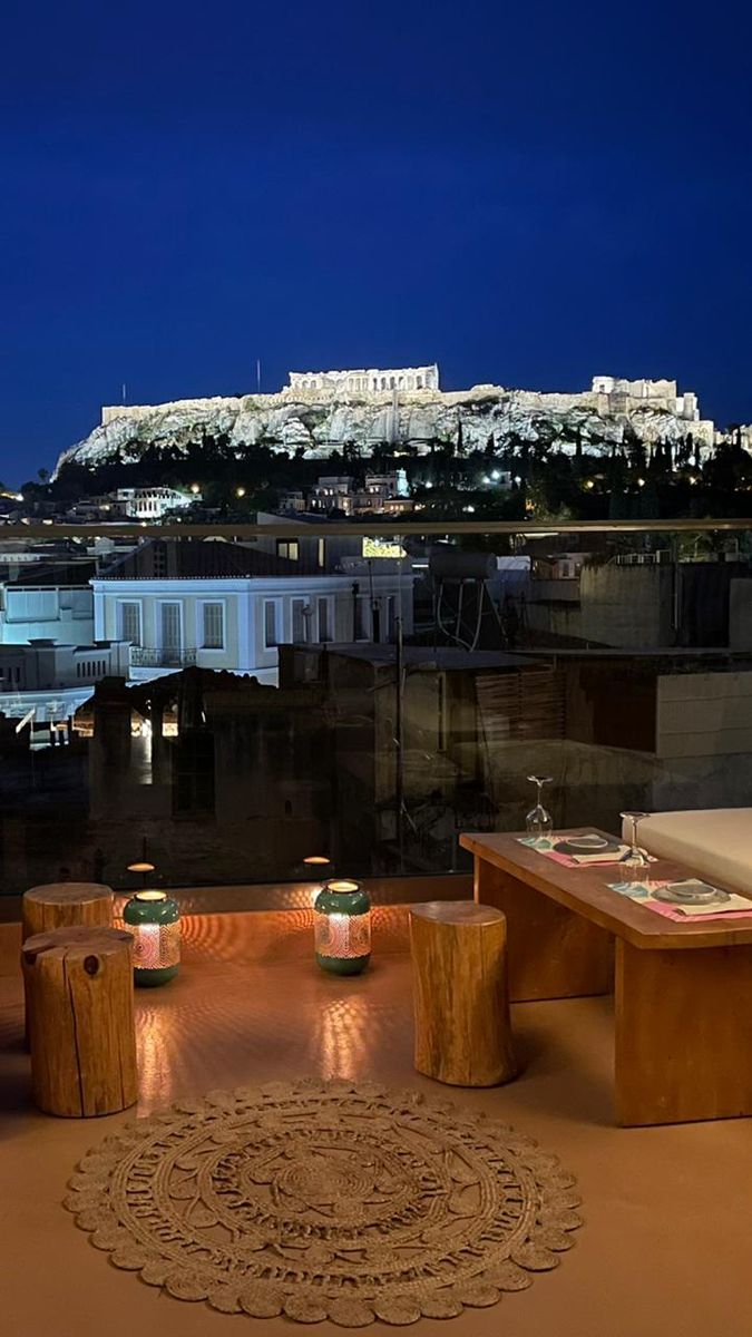 an outdoor dining area overlooking the city at night