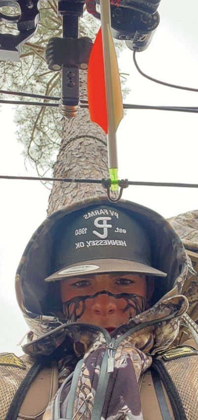 a young child wearing a hat and holding onto a pole with wires in the background