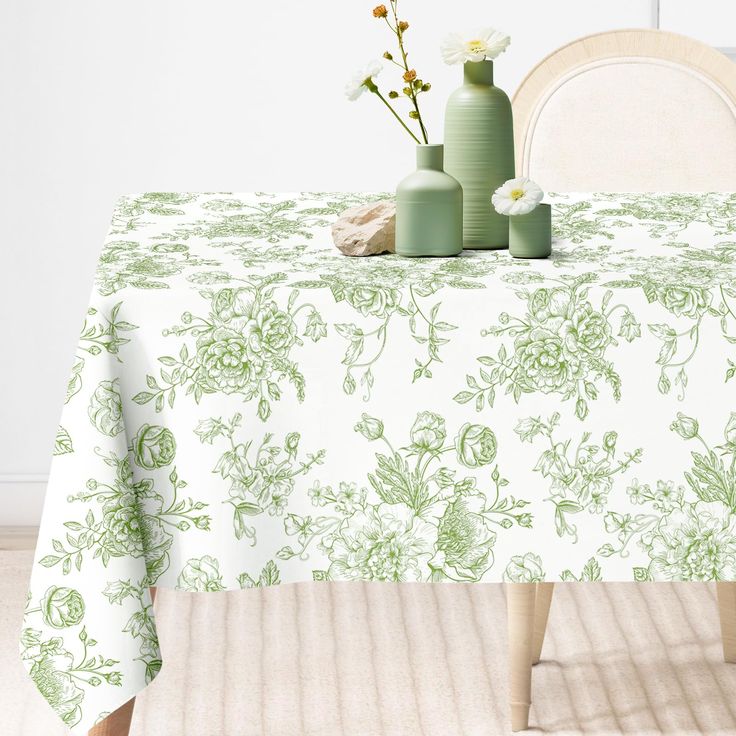 the table cloth is green and white with flowers in vases next to each other