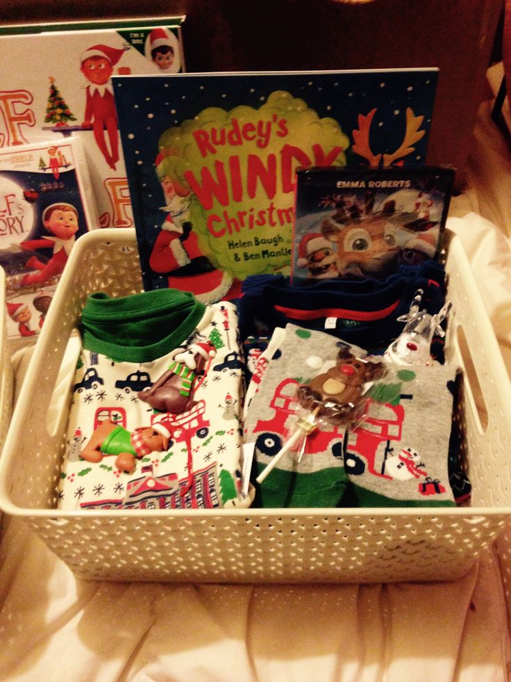 a white basket filled with baby's clothing and books