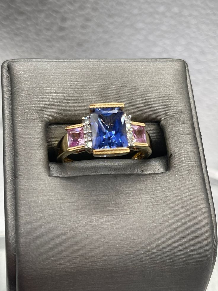 A beautiful ladies multi-gemstone ring designed and made in 10 karat solid yellow gold.  Set with a 2.5 carat rectangular cut Tanzanite stone bordered on each side with four fine white round Diamonds and two princess cut Pink Topaz set one on each side. This is an unusual composition of colored stones that always looks amazing and drips with sparkle. Weight:  4.2 grams Size:  7 ½  Our Price $595.00 Regularly Priced At $900.00 Please See Our Video Remember - If you're purchasing for yourself or a Rectangular Sapphire Ring With Accent Stones, Formal Multi-stone Rectangular Ring, Formal Square Cut Sapphire Ring With Accent Stones, Elegant Multi-stone Rectangular Rings, Rectangular Sapphire Ring With Accent Stones For Formal Occasions, Yellow Gold Rings With Rectangular Accent Stones, Elegant Rectangular Multi-stone Rings, Formal Rectangular Sapphire Ring With Accent Stones, Formal Rectangular Fine Jewelry Gemstones