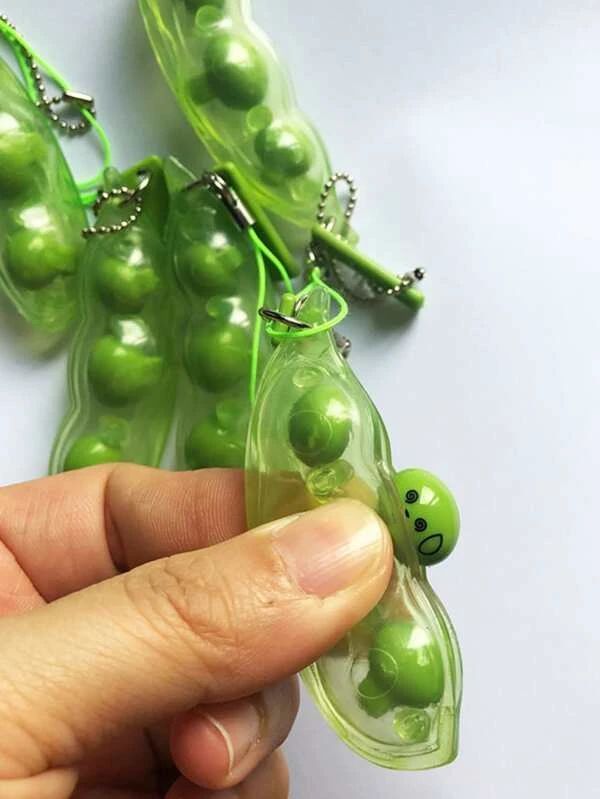 a person is holding some peas with green beads in their hands and one has a smiley face on it