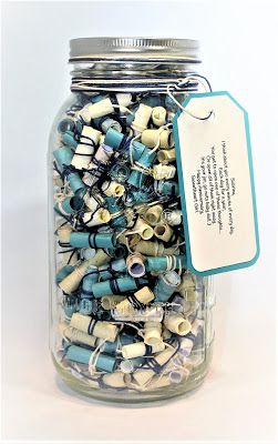 a glass jar filled with lots of different types of beads and wires next to a tag