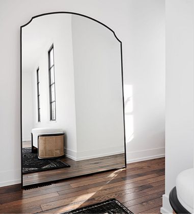 a mirror sitting on top of a hard wood floor next to a white wall and wooden floors