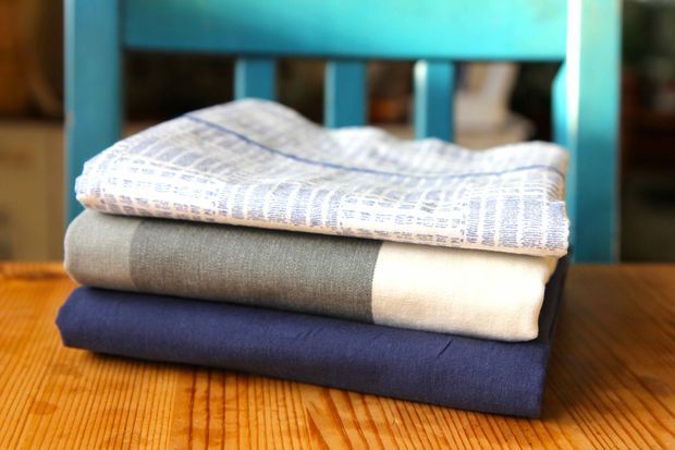 three folded sheets sitting on top of a wooden table next to a blue rocking chair