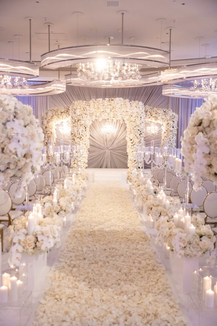 the aisle is lined with white flowers and candles