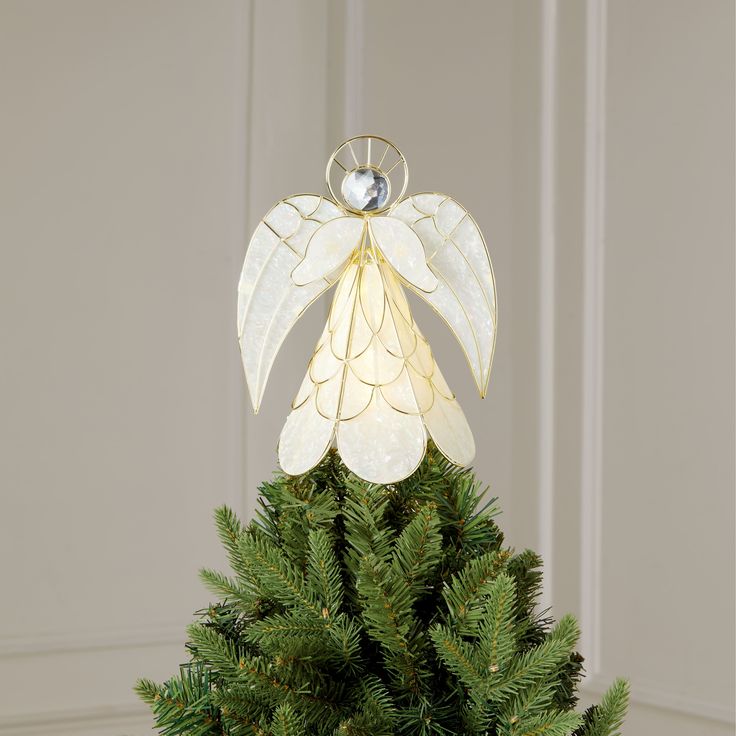 a christmas tree with a white angel decoration hanging from it's top and green branches