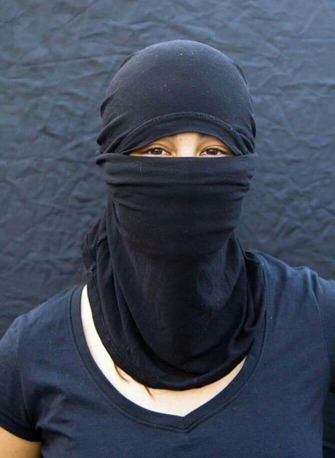 a woman wearing a black head covering over her face and neck, looking at the camera