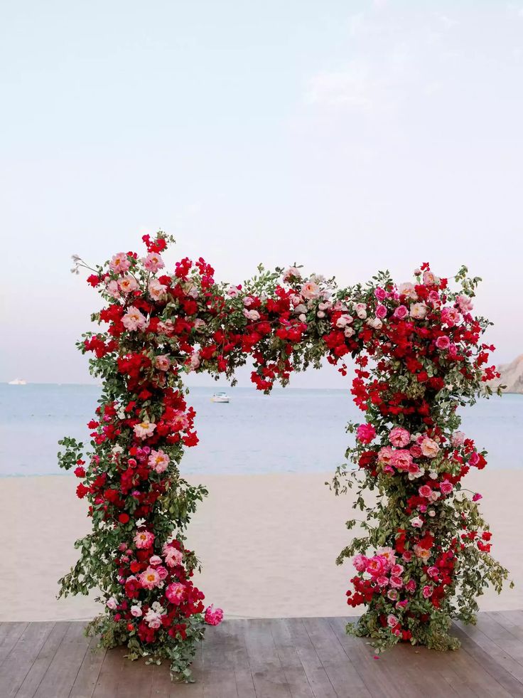 an arch made out of flowers on the beach