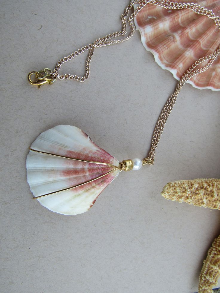 this seashell necklace is a lovely statement piece or pairs well with any of the pieces in our Gadgets and Gizmos collection Gift Pearl Drop Shell Made Of Mother Of Pearl, Pearl Drop Shell, Mother Of Pearl Shell With Pearl Drop As Gift, Shell-shaped Jewelry With Pearl Pendant, Shell-shaped Pearl Pendant Jewelry, White Shell-shaped Jewelry With Pearl Pendant, Handmade White Shell-shaped Pearl Necklace, Handmade Shell-shaped Pearl Necklace Gift, Handmade Shell-shaped Pearl Necklace