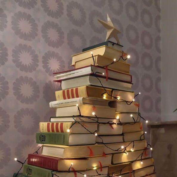 a christmas tree made out of books with lights on it and a star on top