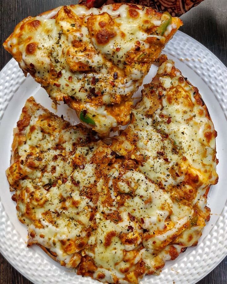 three pieces of pizza on a white plate with sauce and cheese, sitting on a wooden table