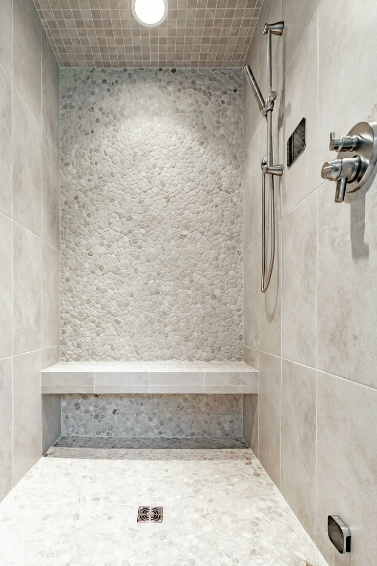 a walk in shower sitting next to a white tiled wall and floor with two faucets on each side