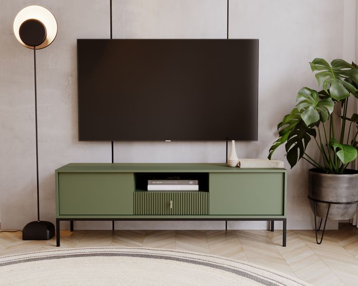 a flat screen tv sitting on top of a green cabinet next to a potted plant