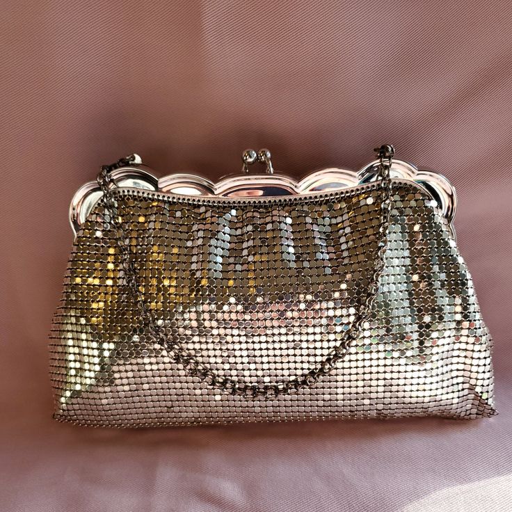 Whiting & Davis wonderfully elegant gilded silver hardware mesh evening bag is accented with a matching gilded silver hardware chain strap which measures 10 inches in length. The length measures 8 inches along the bottom and 5 inches along the top. The height measures 5 1/4 inches, with a width of 1 1/2 inches. Made in the USA. Evening Handheld Shoulder Bag With Chain, Silver Chain Bag For Event, Silver Chain Bag For Wedding, Luxury Rectangular Evening Bag For Dinner, Elegant Bags With Gold-tone Hardware For Gala, Evening Handheld Chain Bag, Luxury Clutch Evening Bag For Dinner, Elegant Shoulder Bag With Chain Strap For Party, Glamorous Clutch Bags For Dinner