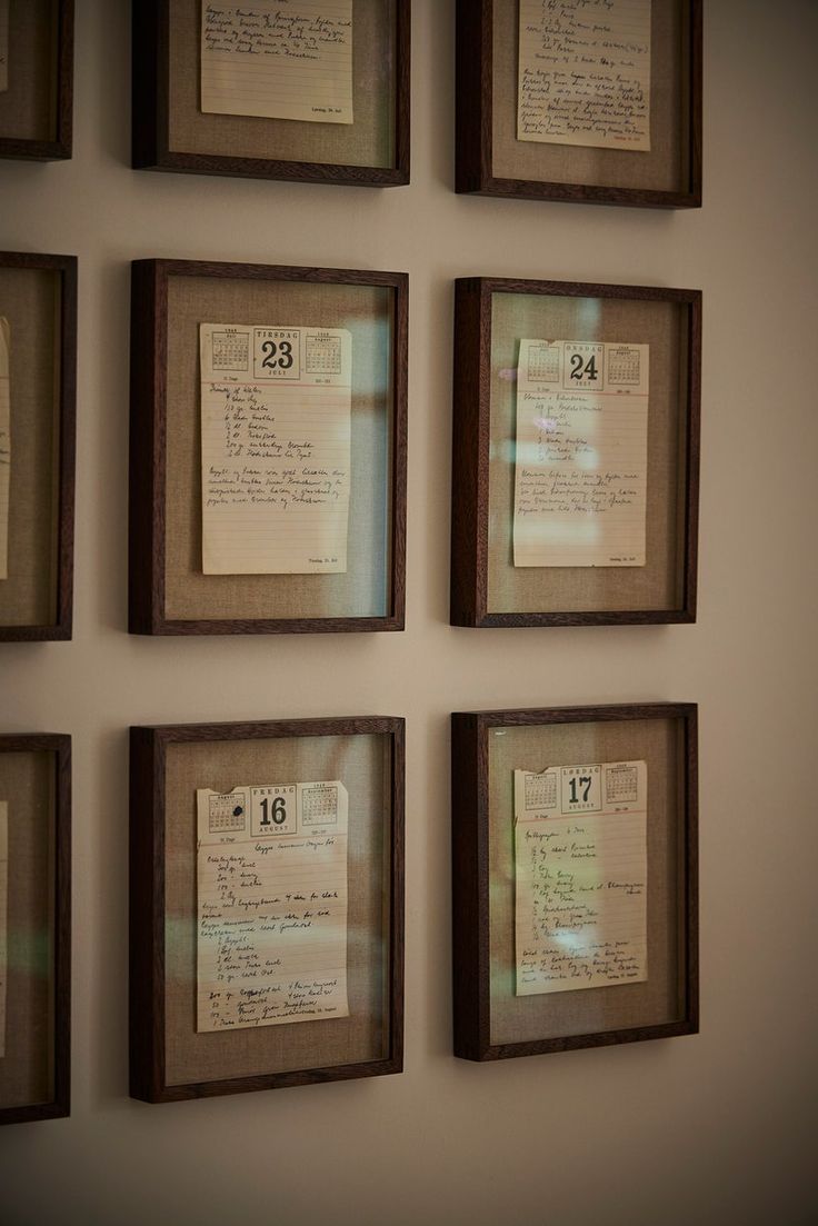 six framed papers are hanging on the wall with numbers and notes attached to them in brown frames