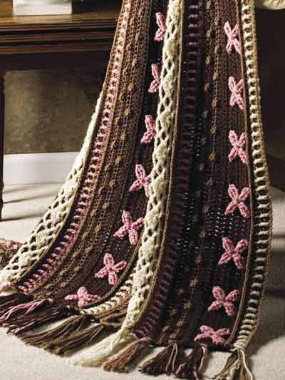 a crocheted blanket sitting on top of a wooden table next to a potted plant