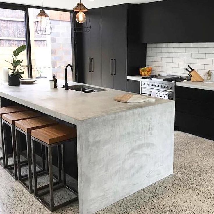 a kitchen with black cabinets and white countertops is pictured in this image, there are three stools at the center of the island