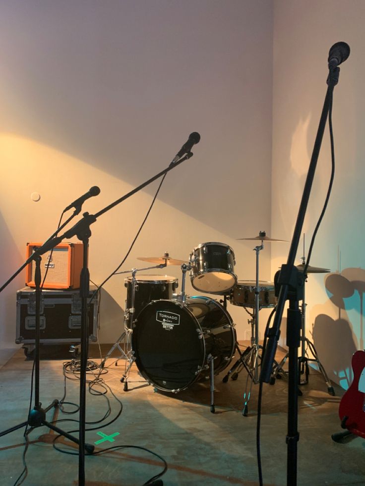 a recording studio with microphones, drums and other musical equipment in front of a wall