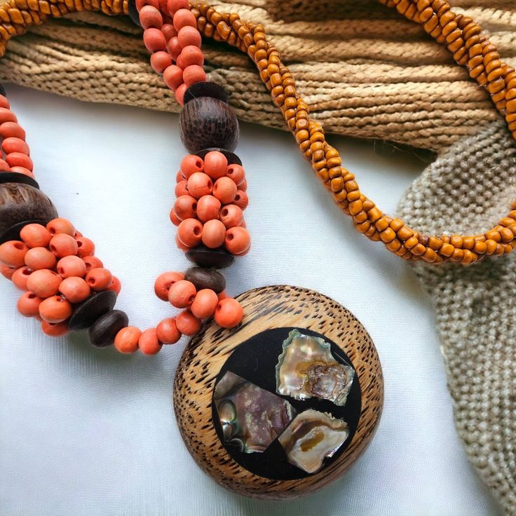 Lovely handmade round wooden, coconut shell and abalone shell pendant/ cluster necklace, orange, green and brown colour, wooden and ceramic beaded. Drop length is approx. 33.5 cm, wooden round pendant is approx. 6 cm. please note this is a Fair Trade product. The wood is of very good quality and will last for a long time. Bohemian Beaded Necklaces With Round Pendant, Bohemian Beads For Festivals And Gifts, Bohemian Beaded Necklace With Round Pendant, Wooden Beads Amulet Jewelry For Festival, Festival Amulet Style Jewelry With Wooden Beads, Amulet Style Jewelry With Wooden Beads For Festival, Bohemian Jewelry With Wooden Beads, Festival Amulet Jewelry With Wooden Beads, Wooden Beads Amulet Necklace For Gift