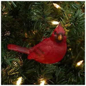 a red bird sitting on top of a christmas tree