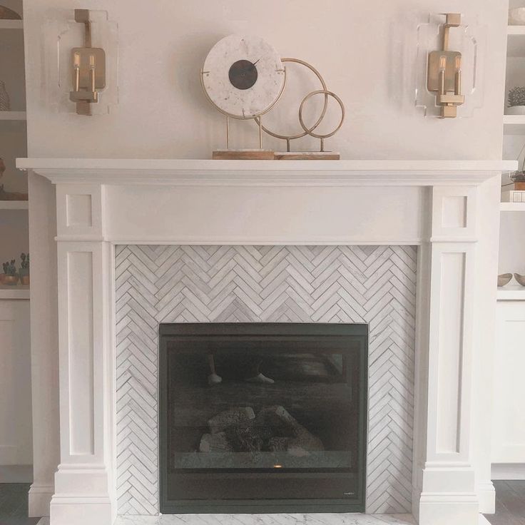 a white fireplace with a clock above it and candles on the mantels behind it