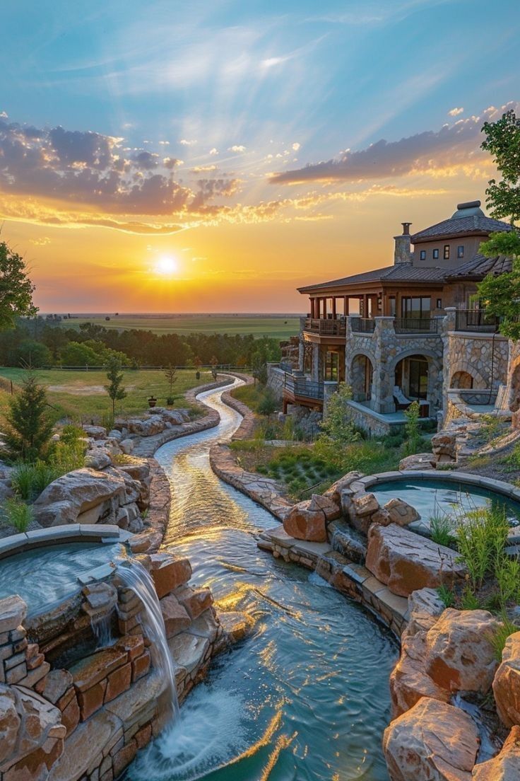 the sun is setting over an outdoor pool with waterfall and hot tub in foreground