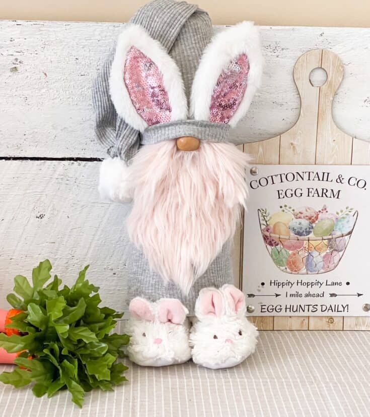 a stuffed bunny is sitting next to a book and some flowers on a table with an egg hunt sign