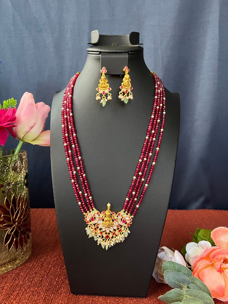 Jadau Kundan Pendant Haram Set/Goddess Lakshmi/Premium Quality/Gold Finish/Ruby Maroon Beads /28 inches Hand Made Haram/Indian Jewelry DETAILS: Includes ; One Haram Two Earrings Extra Chain Links. Necklace: 26. Inches Long, Adjustable length Chain  Closure. Weighs 2.65 oz ( 75 g).  Earrings ; 2 Inches /40.Oz /11 gr Material: Imitation  gold Polish pearls ,Kundan Ruby Emerald Stones. Finish: Premium  Quality Gold finish.  NOTE: I try my best to show you photos of my products as they appear in real life, but please note that variations in color occur due to differences in lighting and screen settings.  PRODUCT CARE: - Avoid contact with heat/fire, water, and chemicals such as perfumes or any sprays to prevent product damage.  - Store wrapped in butter paper, cotton cloth, or the provided box Multicolor Temple Necklace For Puja Festivals, Festive Kundan Necklace For Puja, Multicolor Cutdana Temple Necklace For Navratri, Spiritual Festive Cutdana Temple Necklace, Temple Necklace With Meenakari Round Beads For Puja, Multicolor Temple Jewelry Mala For Puja, Meenakari Temple Necklace With Round Beads For Puja, Spiritual Kundan Necklace With Meenakari For Festive Occasions, Temple Necklace With Meenakari For Puja