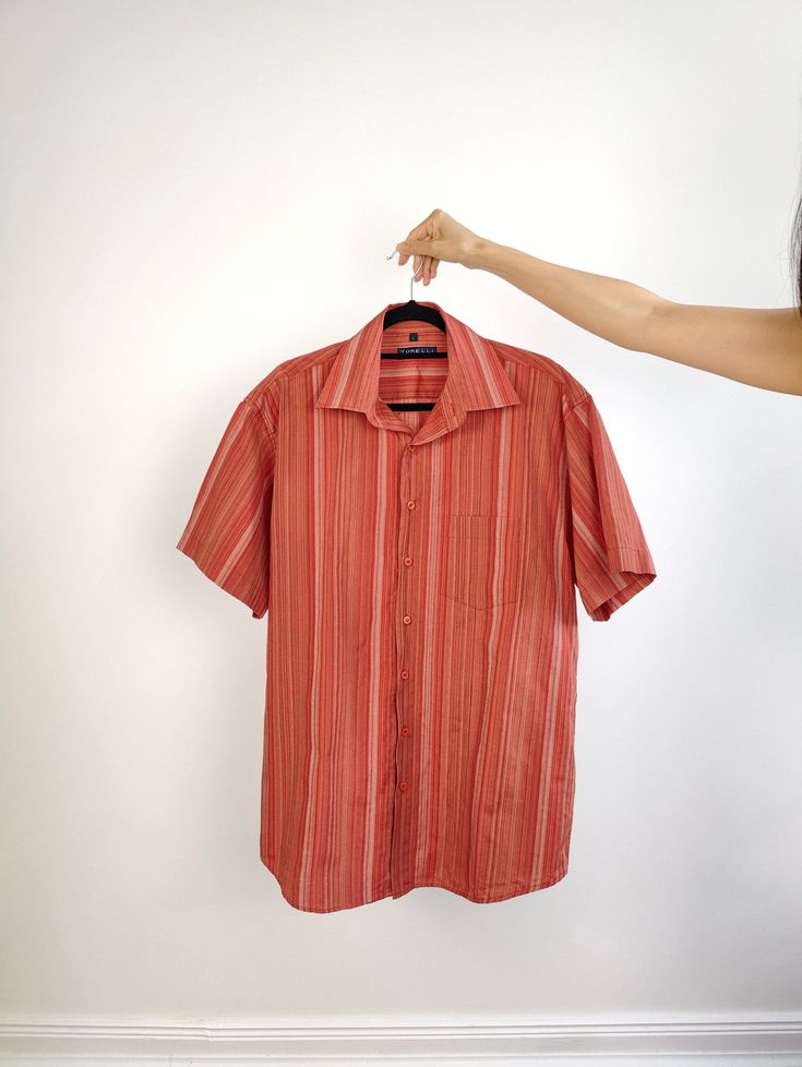 DESCRIPTION The Cotton Blend Red Orange Stripe Shirt is a cool vintage men oversized short sleeves shirt in a bright orange red stripe pattern. Made by the brand Torelli, this quality piece is made from a thicker luxurious cotton blend fabric.  CONDITION This vintage shirt is in a great vintage condition with light stains on the front (see close up picture) SIZING This vintage shirt is labelled as size men L > Please check measurements below before purchasing as all vintage sizes are different Measurements: Arms till shoulder seam: 25cm Shoulder till shoulder seam: 51cm Armpit to armpit: 59cm Back: 86cm Model has size XS in tops and is 1m65 MATERIAL 60% cotton 40% polyester BRAND Torelli WITH LOVE  All vintage fashion for women are washed and shipped from Berlin with a lot of love All vint Striped Cotton Short Sleeve Shirt, Red Short Sleeve Tops With Vertical Stripes, Striped Cotton Shirt With Short Sleeves, Summer Short Sleeve T-shirt With Vertical Stripes, Summer Vertical Stripes Short Sleeve T-shirt, Vertical Stripes Relaxed Fit Short Sleeve Shirt, Relaxed Fit Shirt With Vertical Stripes And Short Sleeves, Relaxed Fit Short Sleeve Shirt With Vertical Stripes, Relaxed Fit Shirt With Vertical Stripes