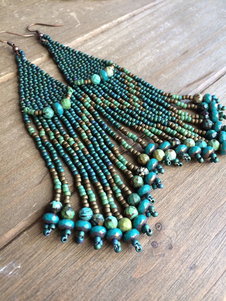 a close up of a necklace on a wooden surface with beads and chains hanging from it