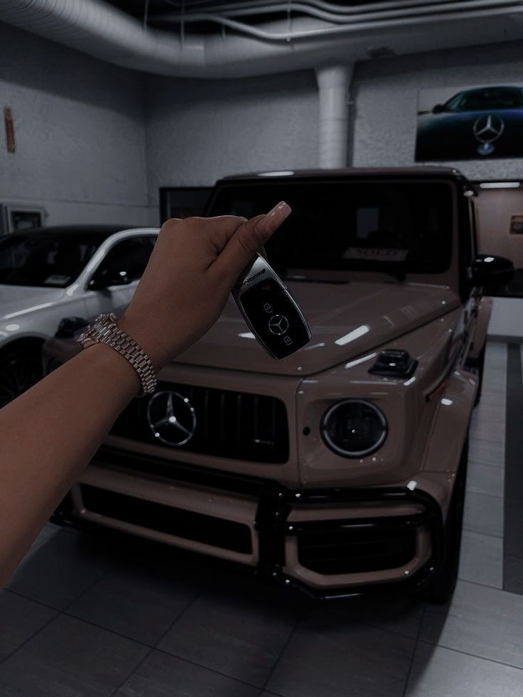 a hand pointing at a car in a garage