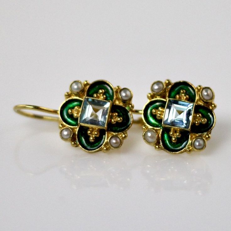 This unique Arts & Crafts Movement design showcases an onyx, iolite, blue topaz, emerald, or garnet set in a cloverleaf of emerald-green or royal blue enamel work, accented with cultured pearl. 24k gold over sterling silver. European back for pierced ears. Size: 3/4 inch. Elegant Turquoise Enamel Earrings, Heirloom Round Jeweled Jewelry, Enamel Gemstone Jewelry For Anniversary, Elegant Gemstone Earrings With Enamel, Elegant Enamel Earrings With Gemstones, Exquisite Turquoise Jewelry For Formal Occasions, Hallmarked Enamel Jewelry For Weddings, Blue Emerald Jewelry For Formal Occasions, Blue Emerald Jewelry For May Birthstone