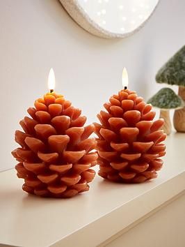 two pine cone candles sitting on top of a table