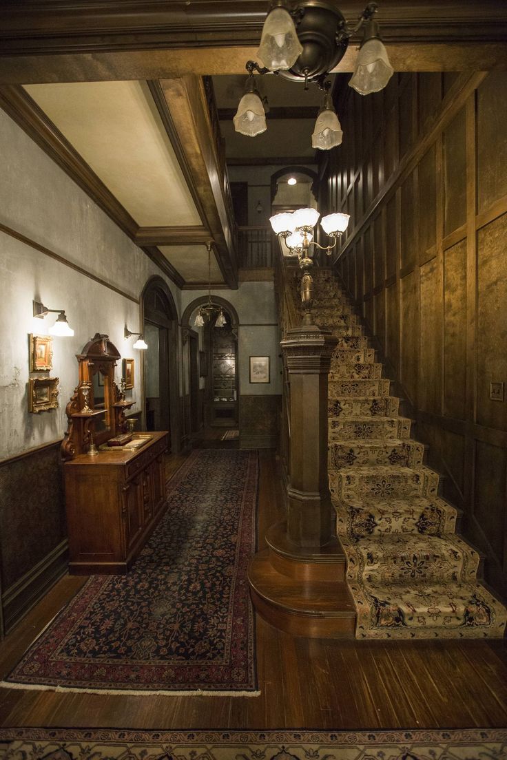 a staircase leading up to the second floor in a house with wood paneling and chandeliers