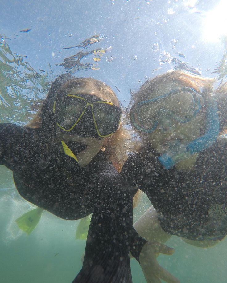 two girls wearing scuba gear and snorkels under the water