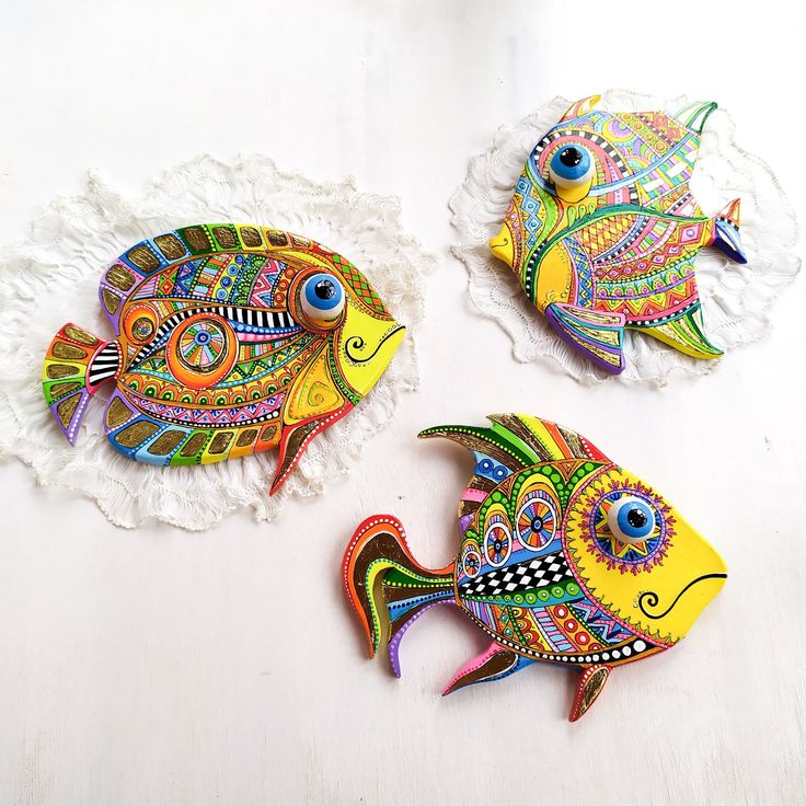 three colorful fish are sitting next to each other on a white doily with lace