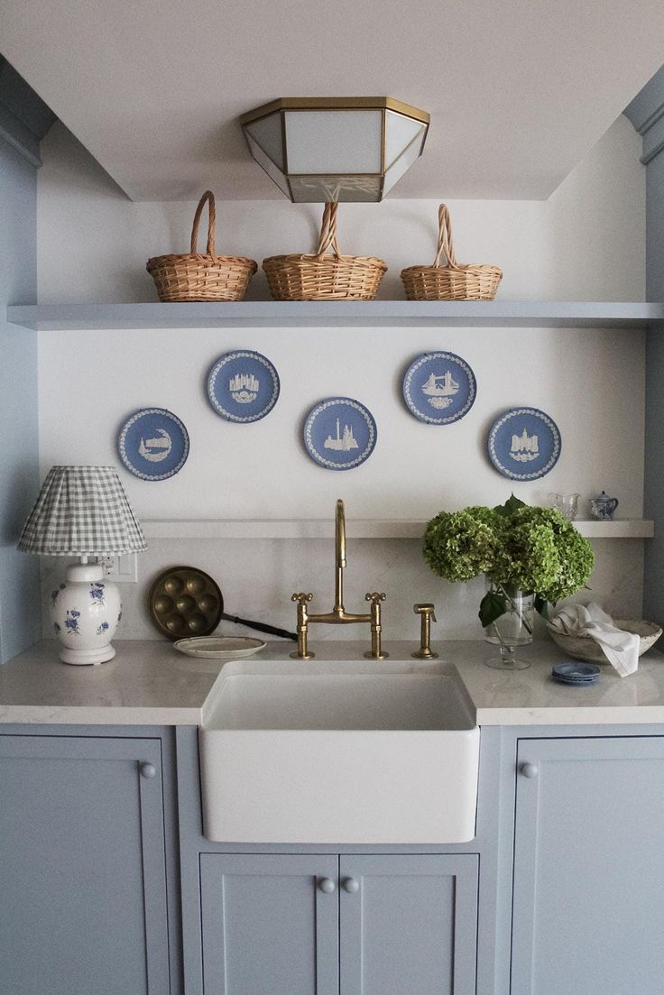 a kitchen with blue and white plates on the wall above the sink, along with other dishes