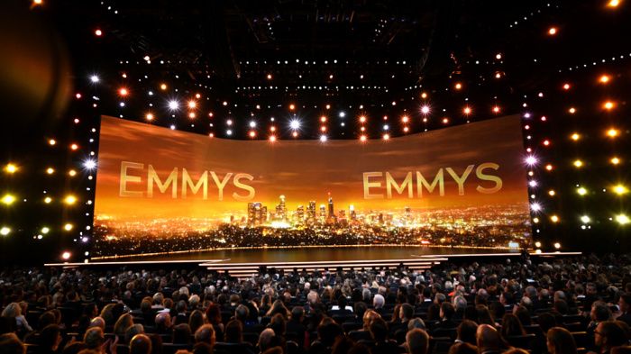 an empty stage with the words emy's on it and people sitting in chairs