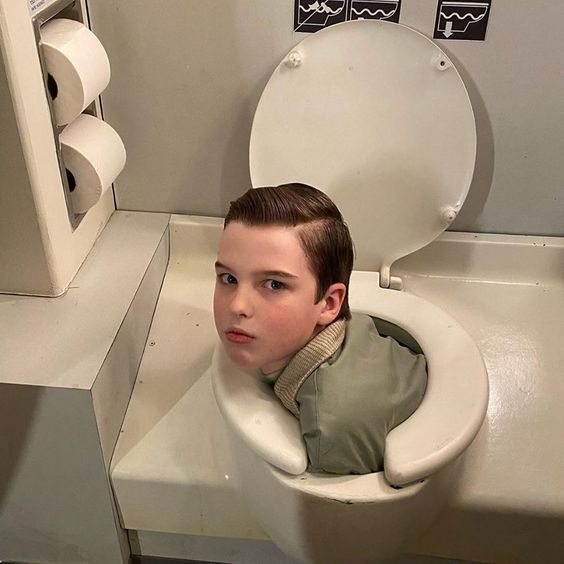 a young boy is sitting in a toilet