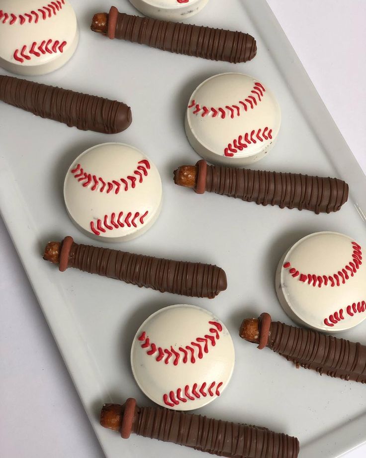 baseball themed cupcakes are arranged on a white platter with chocolate sticks in the batter's mitts